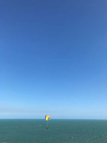 leisure activities person paragliding above blue sea during daytime gliding